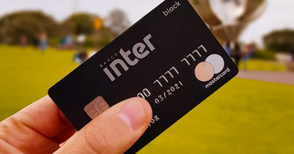 Mão segurando cartão inter black.